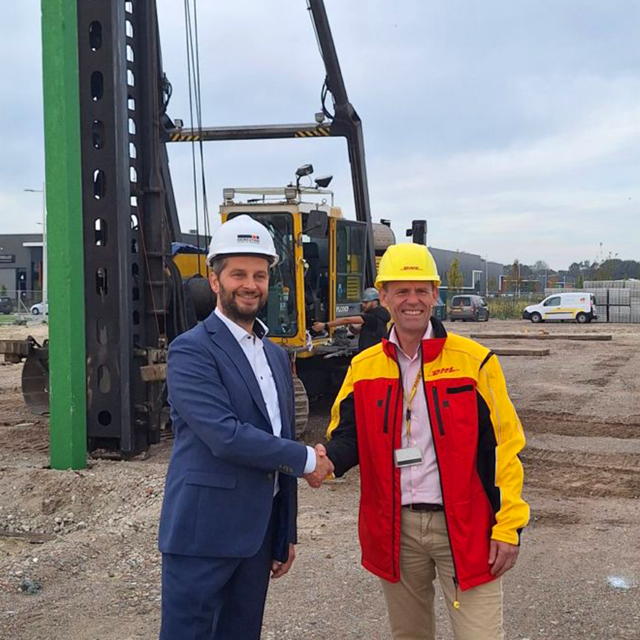 Wethouder Economie André Flach feliciteert Hugo de Ridder van DHL met het slaan van de "groene paal".